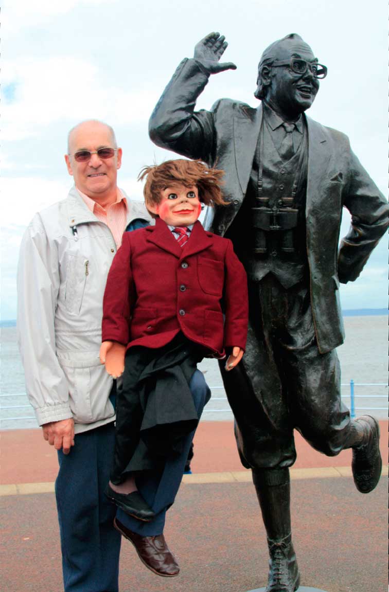 Mike with Charlie, Eric’s old ventriloquist’s dummy, next to Eric’s statue at Morecambe