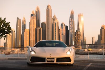 White sports car parked in front of the skyline of a city.