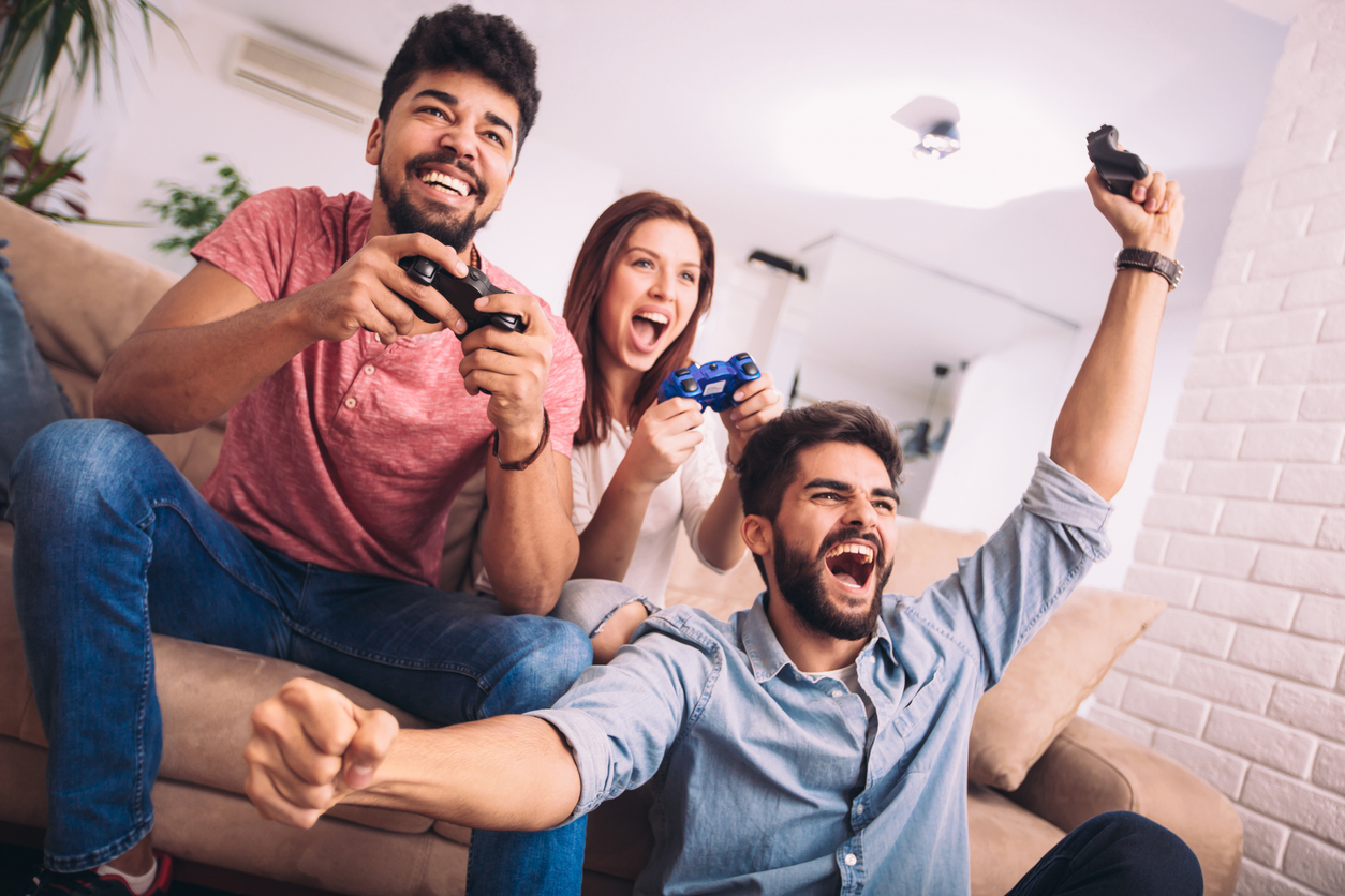 Group of friends play video games together having fun at home