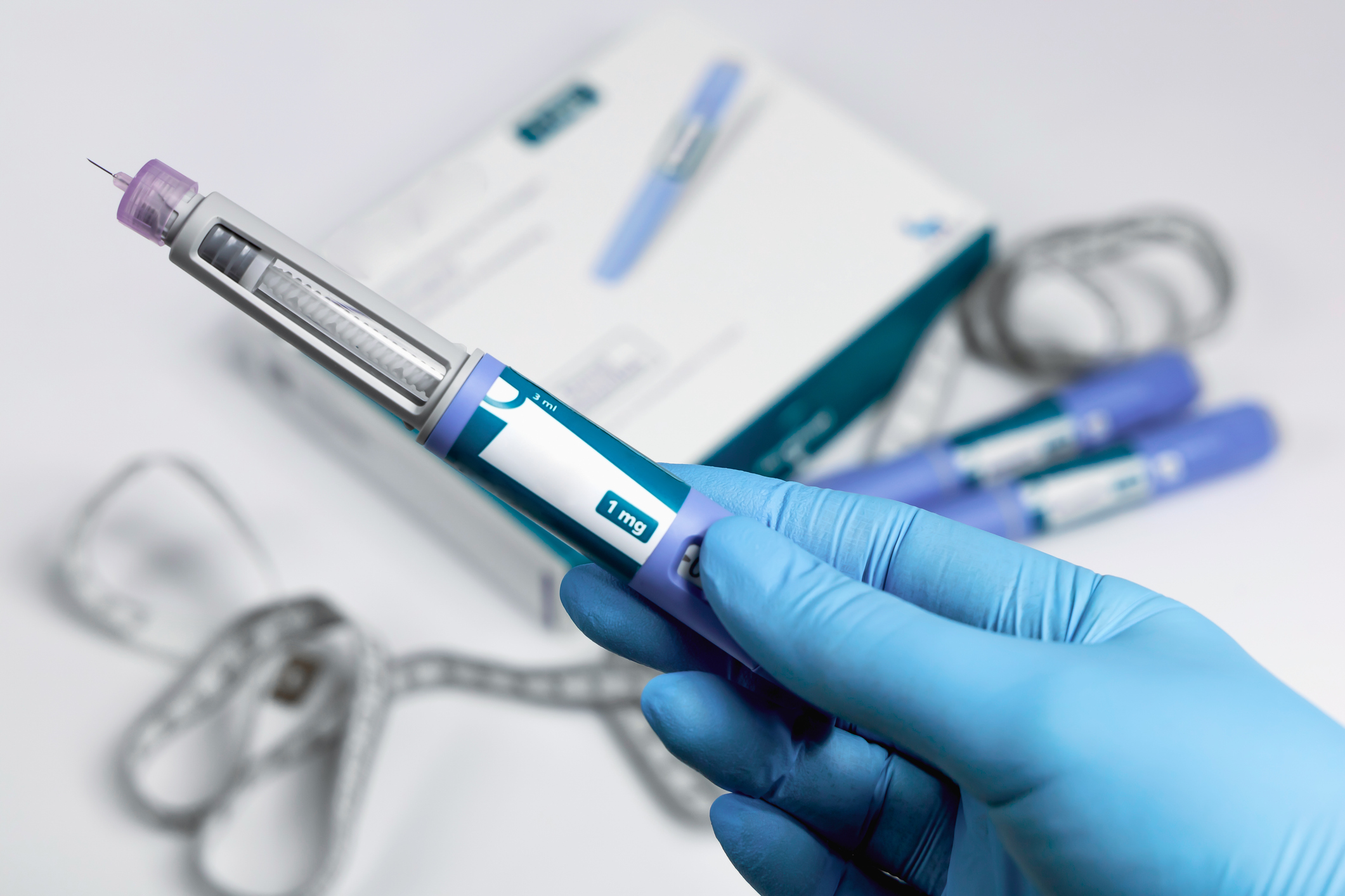 Hands in blue surgical gloves holding Ozempic Insulin.