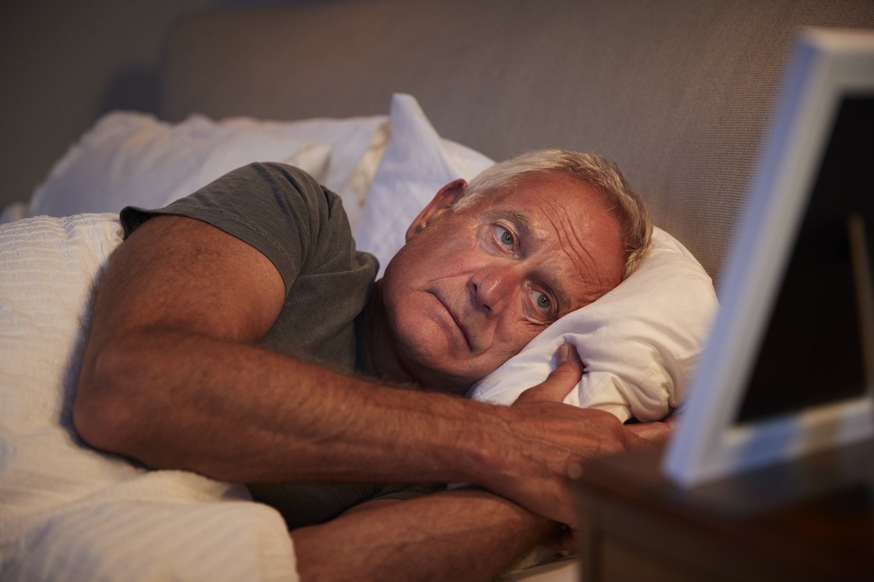 Sad man in bed looking at picture frame