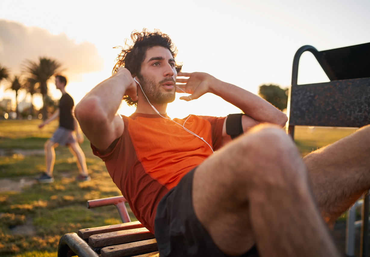 Fitness young man doing exercises on public equipment in the park