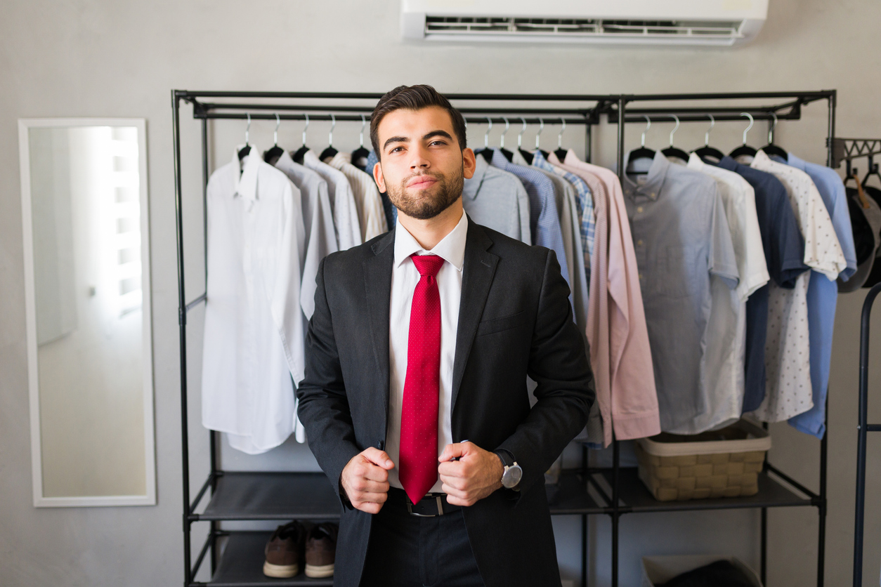 Confident businessman adjusting his suit while standing in his modern walk in closet at home