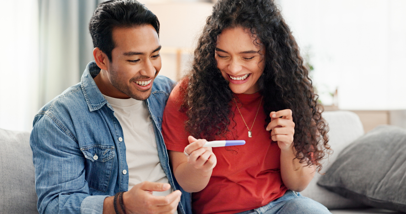 Pregnancy test, happy and couple on sofa excited for fertility 
