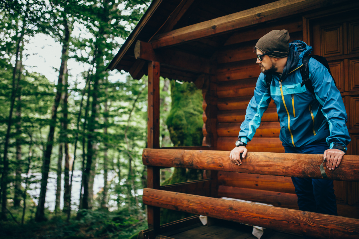 Man standing at the balcony of wooden house in forest