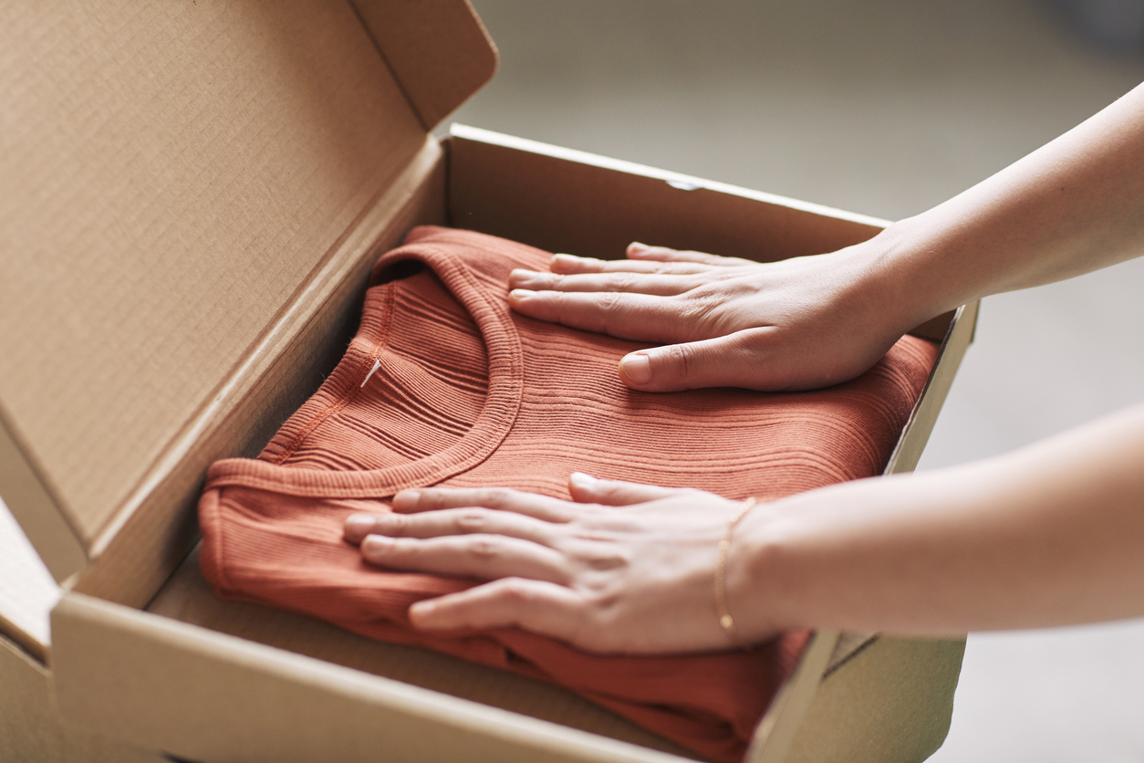 Close-up of woman opening parcel with new red shirt