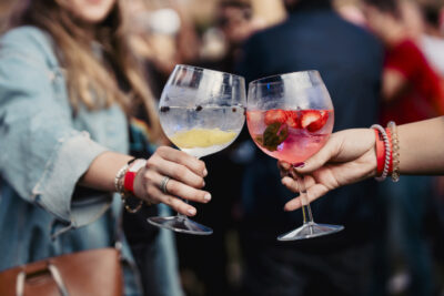 Two women holding a gin and tonic and toasting during a music festival. High quality photo