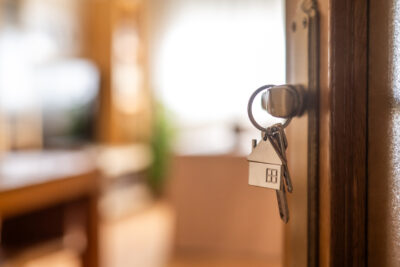 House-shaped keys are hanging from the door knob of a new home, representing the exciting moment of acquiring property and starting a fresh chapter