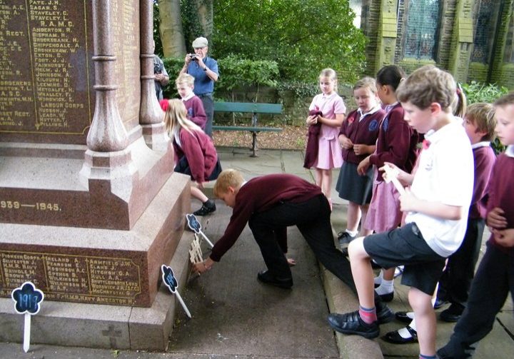 A pupil lays a wooden cross at the War Memorial