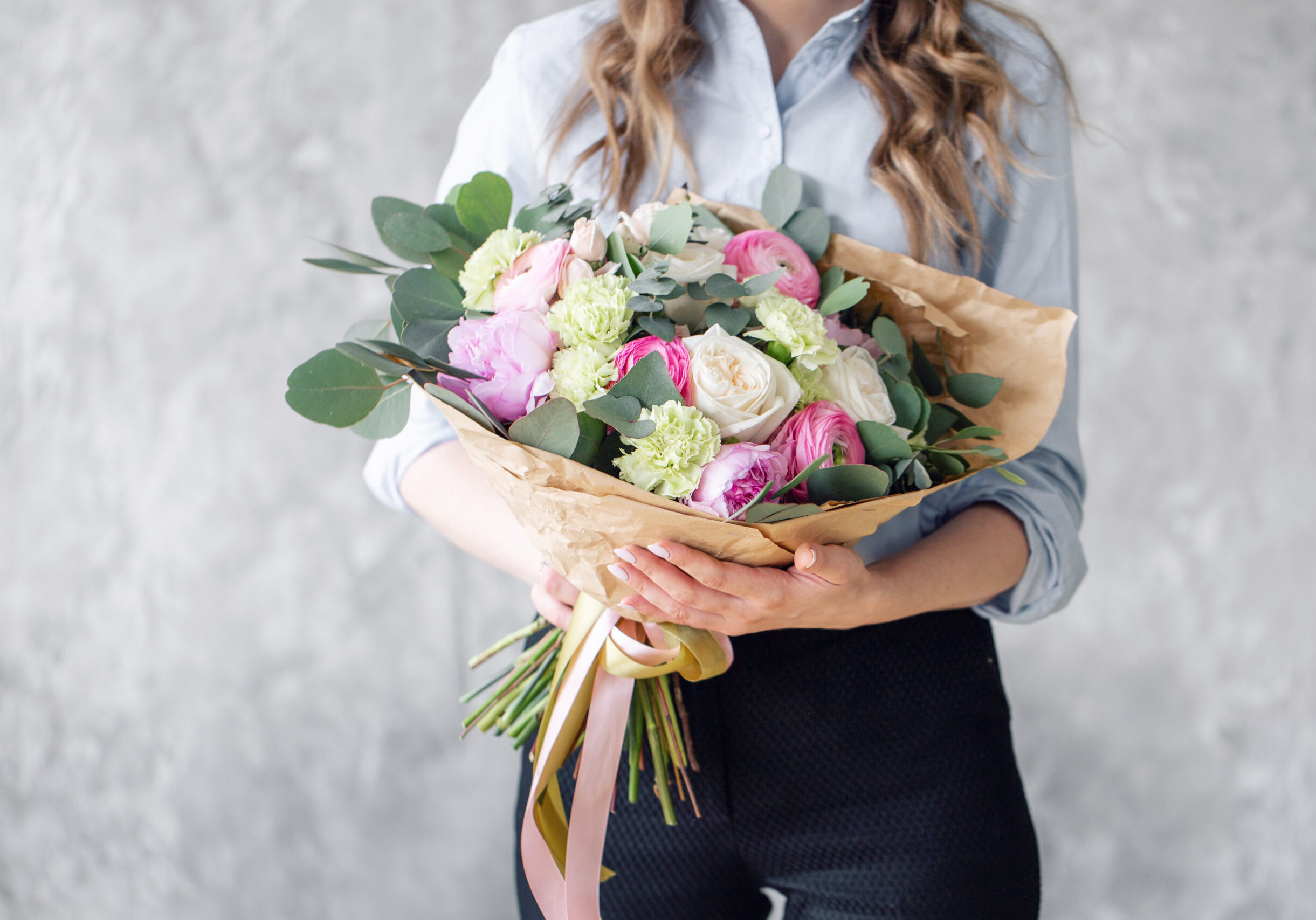 Woman florist creating beautiful bouquet in flower shop. Working in flower shop. Girl assistant or owner in floral design studio, making decorations and arrangements