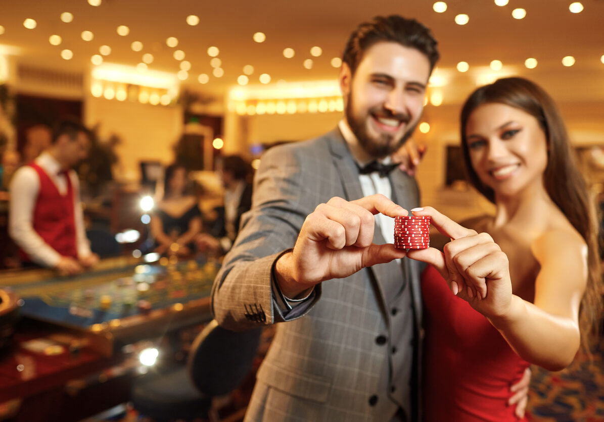 Happy couple holding roulette chips in their hands. A couple of gambling games. Concept Casino.