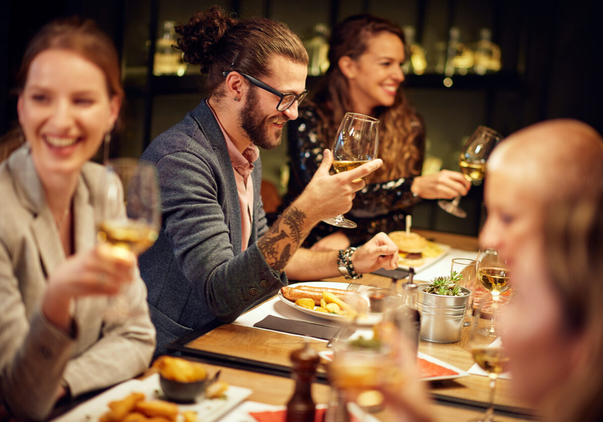 Group of best friends sitting in restaurant, having dinner, drinking wine and having fun.
