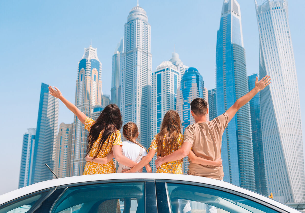 Family of four on car vacation on background of skyscrapers in Dubai