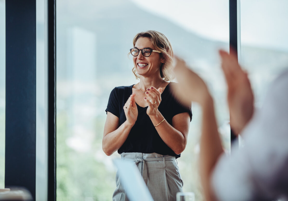 Businesswoman clapping hands after successful brainstorming session in boardroom. Business people women applauding after productive meeting.