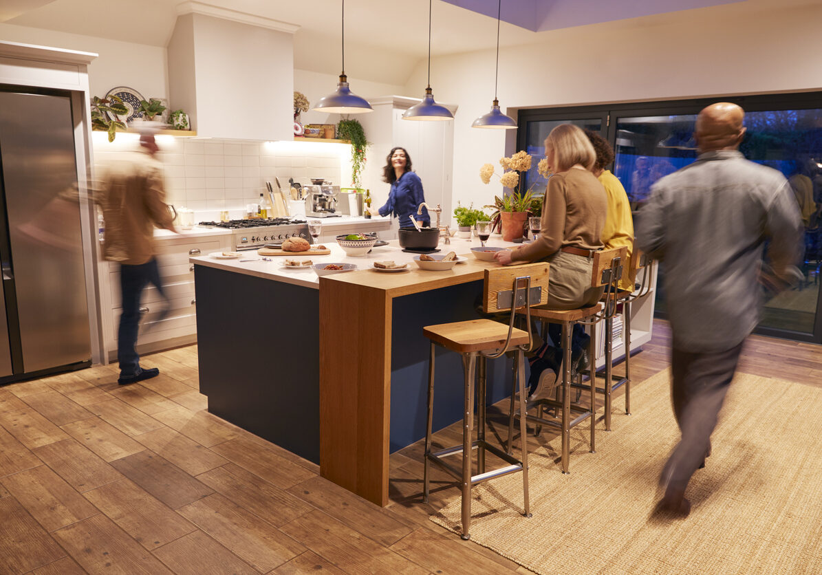 Motion Blur Shot Of Mature Friends Meeting At Home For Evening Dinner Party