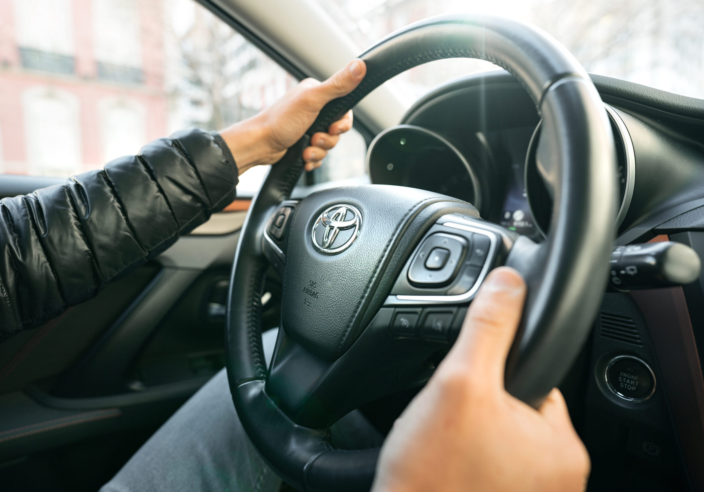 Man driving Toyota car. Close up of steering wheel with driver hands. Lisbon, Portugal. 07.01.2021. High quality photo