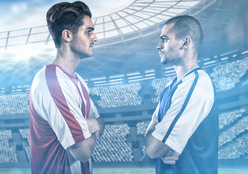 Confident football players looking at each other against view of a stadium