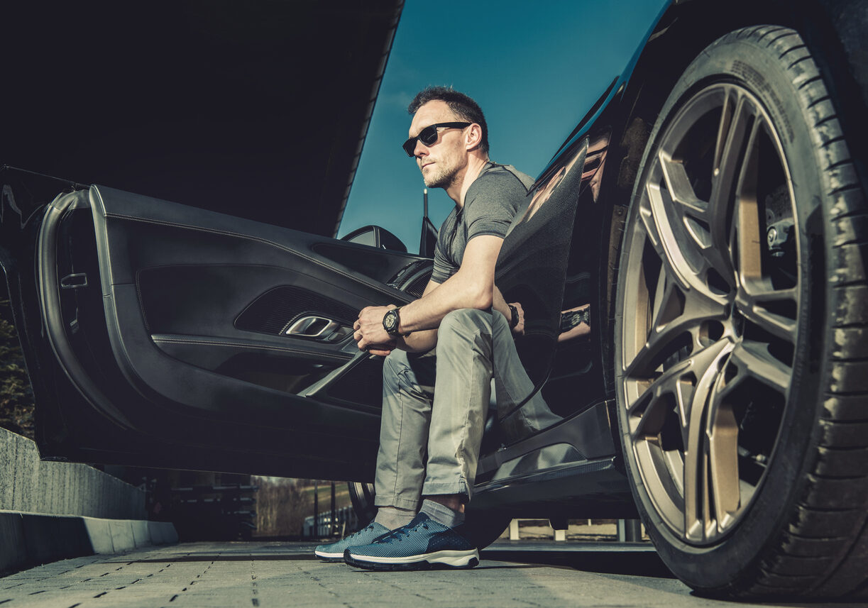 Caucasian Driver in His 40s Seating Inside His Modern Exotic Sporty Car and Enjoying Warm Summer Weather. Road Trip Theme.