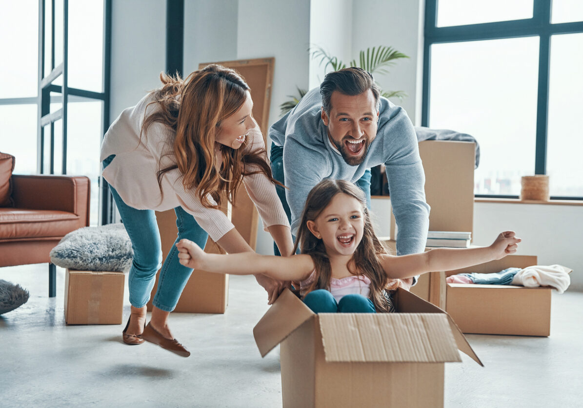 Cheerful young family smiling and unboxing their stuff while moving into a new apartment