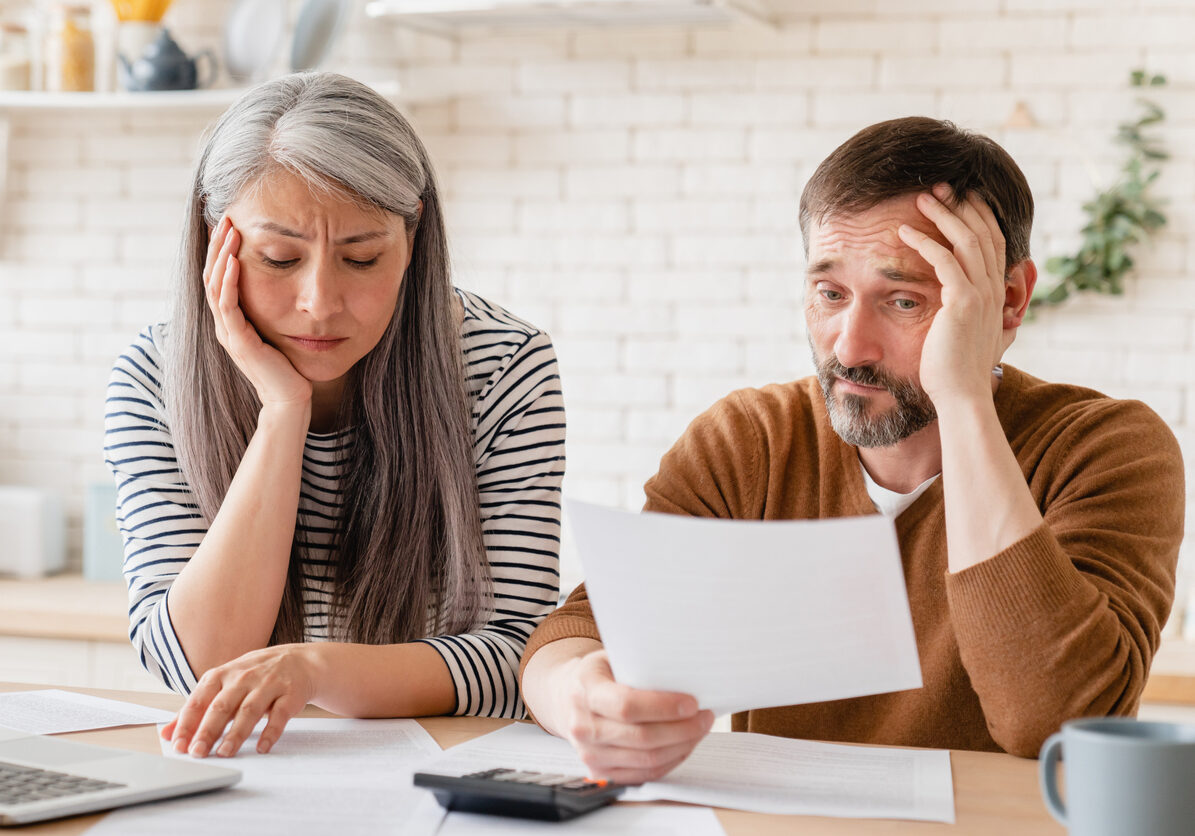 Sad disappointed mature middle-aged couple family wife and husband counting funds, savings, declarations, investments,paperwork, financial documents, bankruptcy, court case, bills, pension at home.