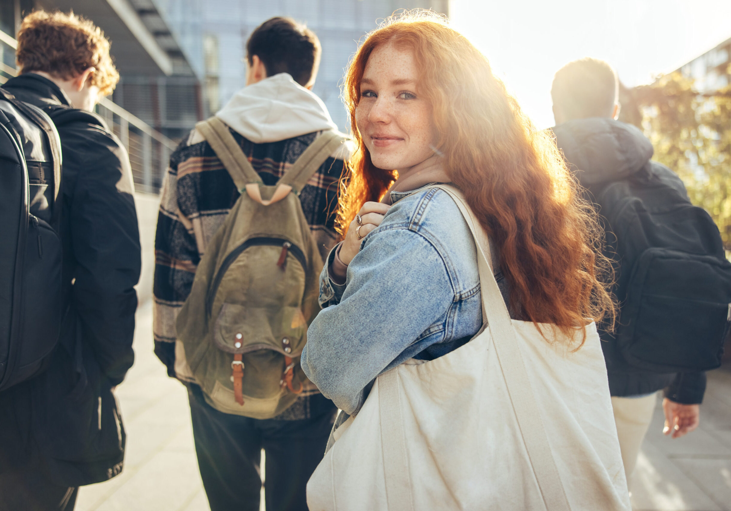 Female student glancing back while going for a class in college. Girl walking with friends going for class in high school.
