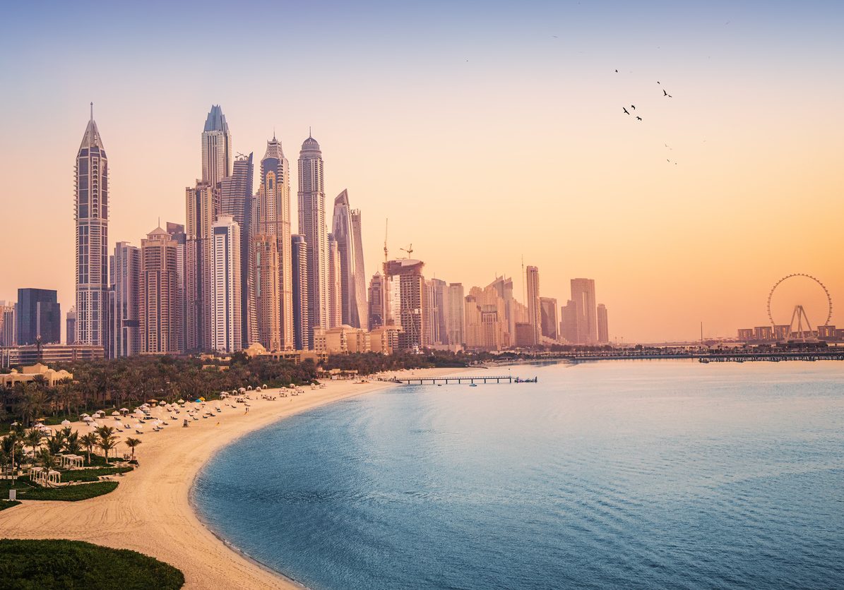 Sunset view of the Dubai Marina and JBR area and the famous Ferris Wheel and golden sand beaches in the Persian Gulf. Holidays and vacations in the UAE