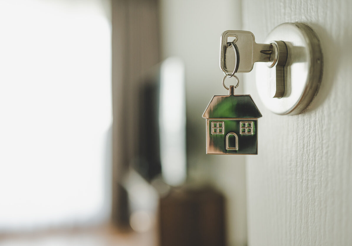 Open the door and door handle with a key and a keychain shaped house. Property investment and house mortgage financial real estate concept