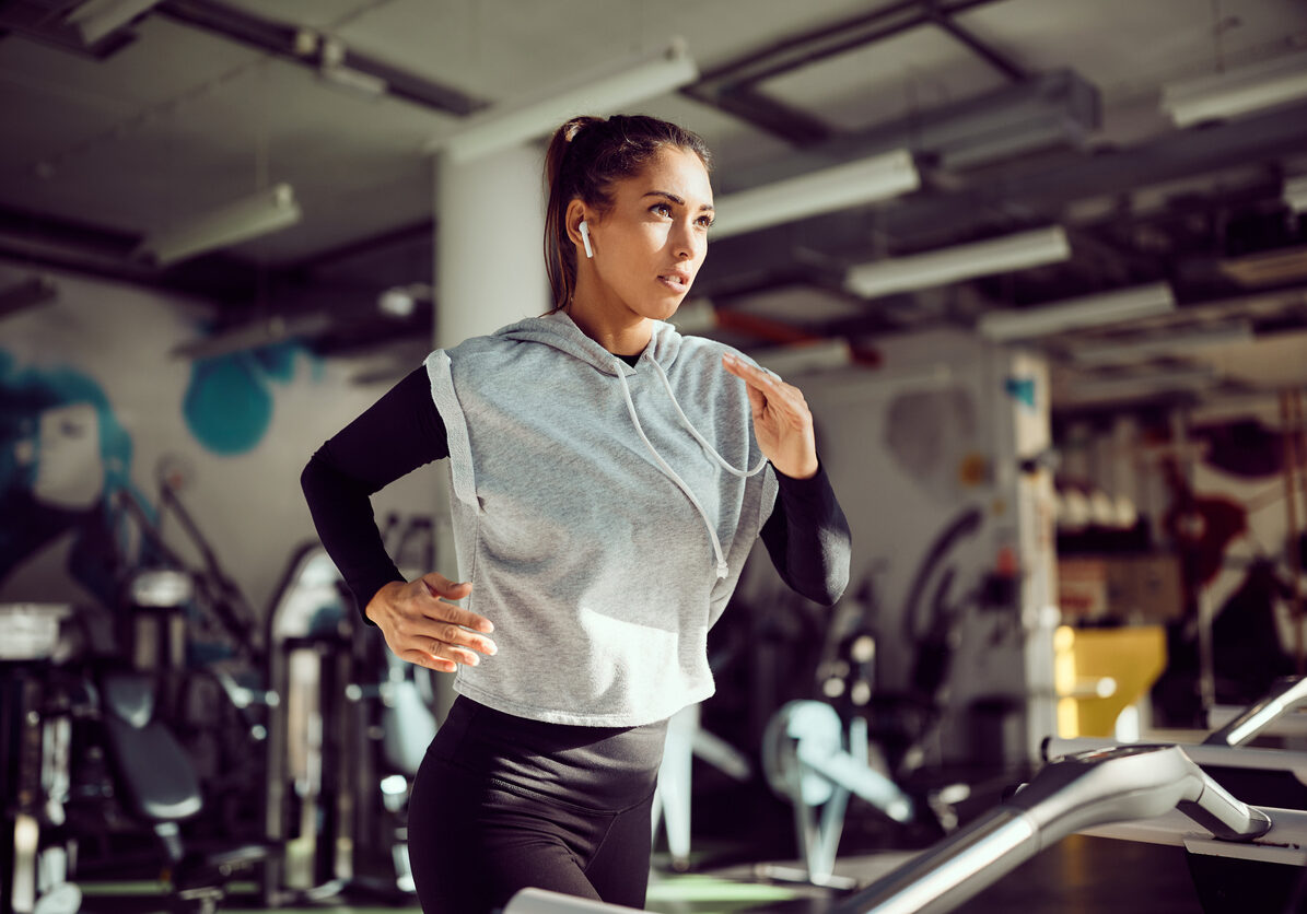 Young female runner exercising on treadmill in a gym.