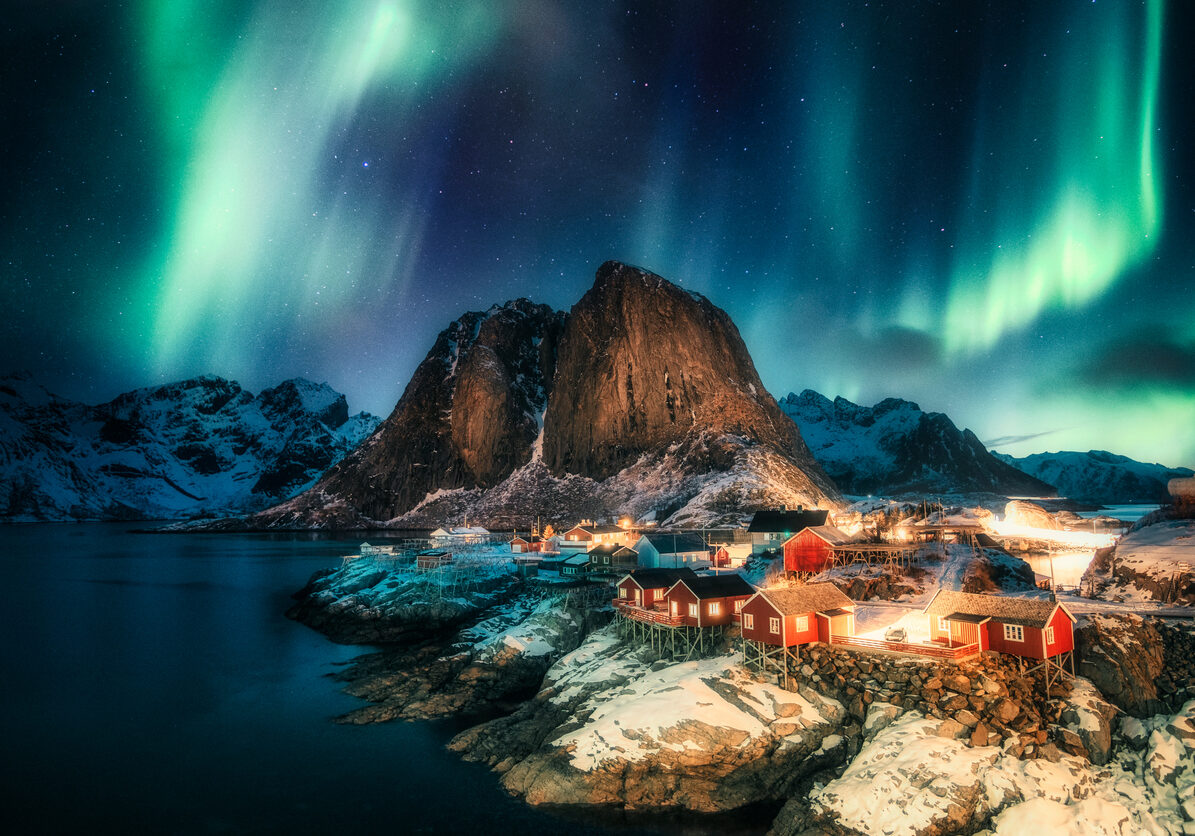 Aurora borealis, Northern lights over mountain with fishing village on coastline at Hamnoy, Lofoten islands