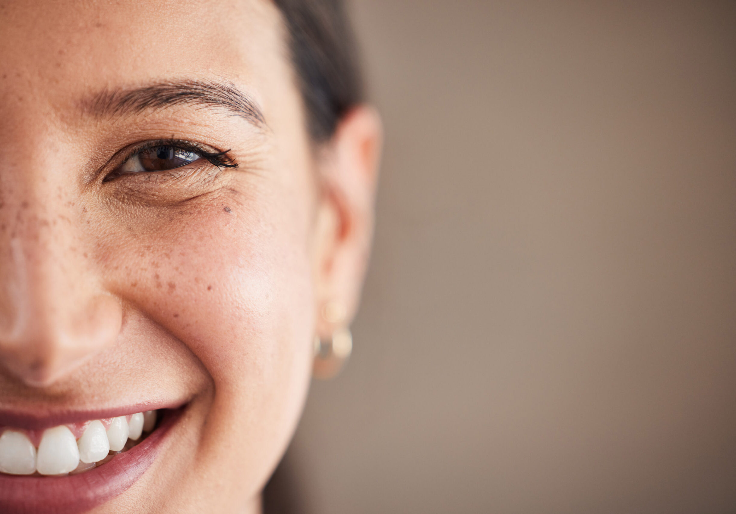 Face of beautiful mixed race woman smiling with white teeth.  Portrait of a woman's face with brown eyes and freckles posing with copy-space. Dental health and oral hygiene