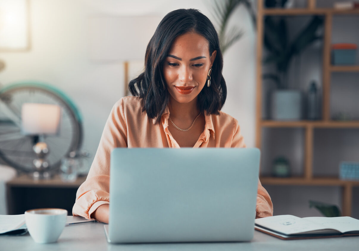 Woman working on laptop online, checking emails and planning on the internet while sitting in an office alone at work. Business woman, corporate professional or manager searching the internet