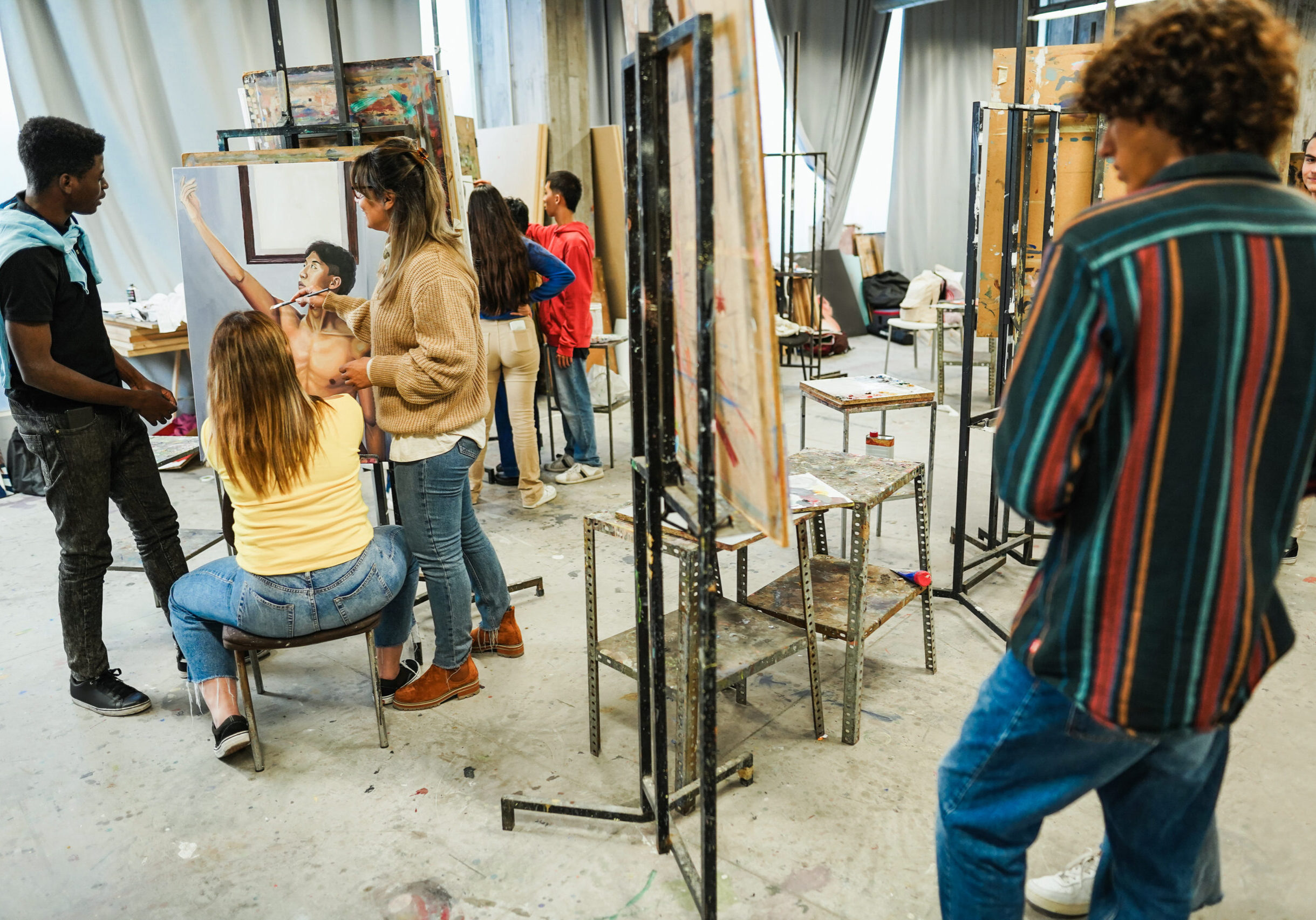 Mature teacher working with art students during painting class at school - Focus on teacher face