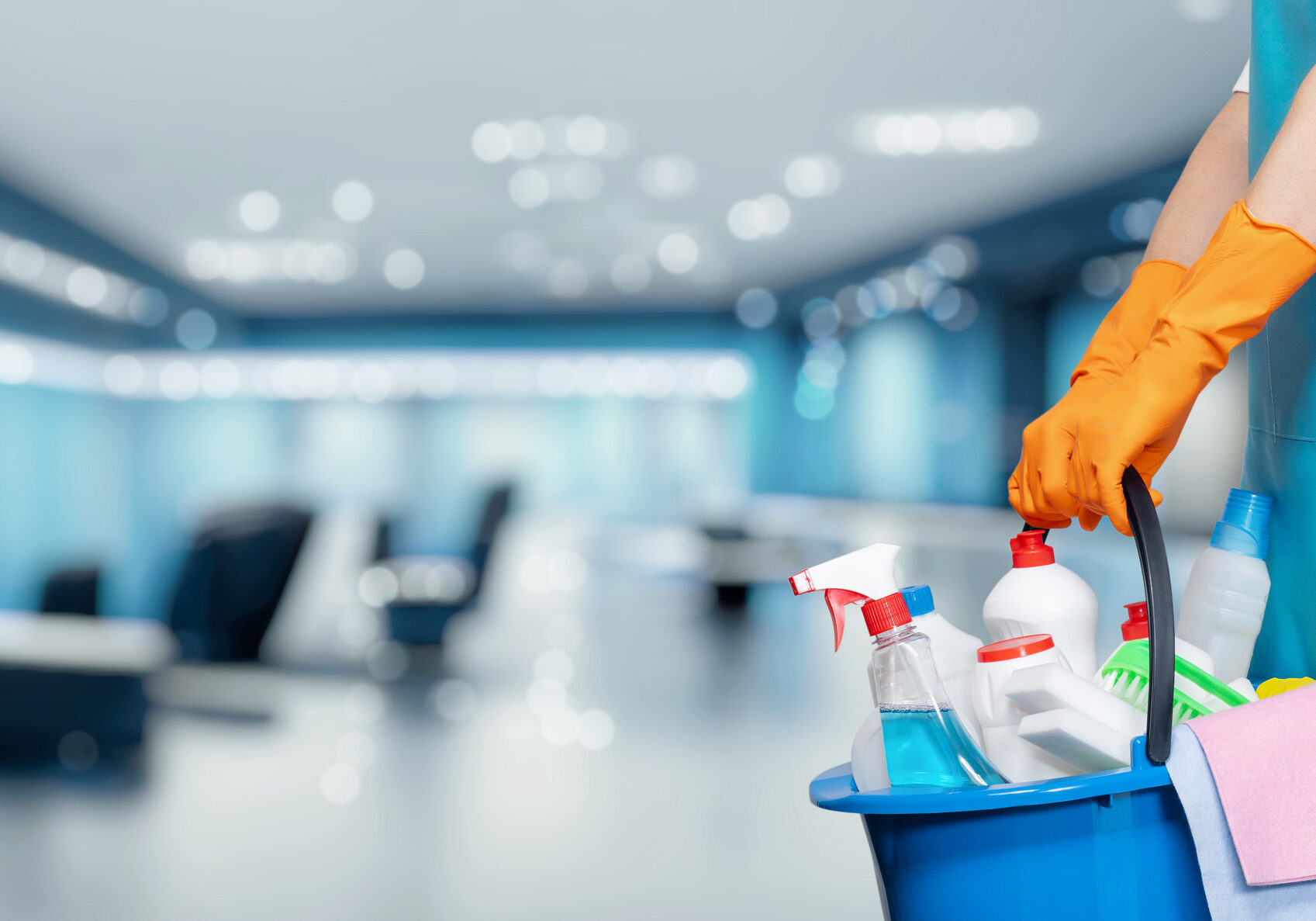 Concept cleaning service business premises. Cleaning lady holding a bucket of cleaning products against the backdrop of an office in a business center.