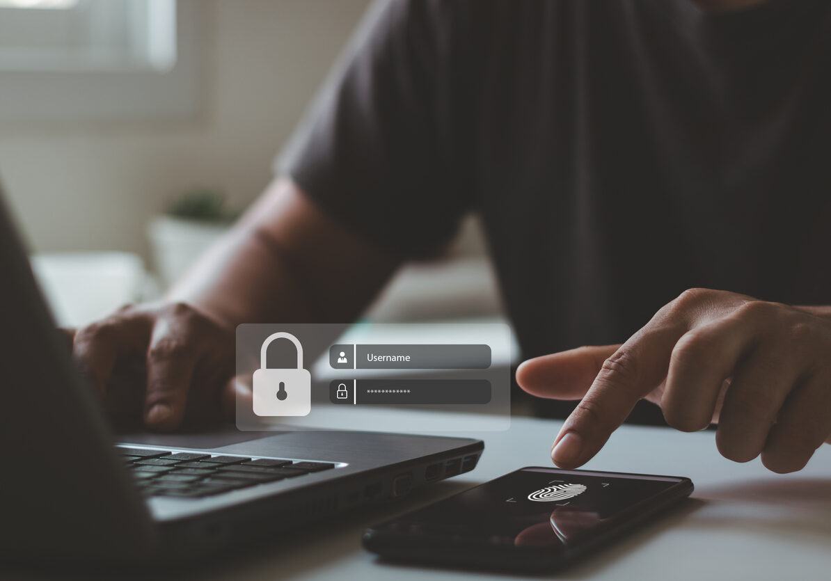 Business Security in a Digital Age. Businessman Ensuring Protection with Finger scan and Multi-Factor Authentication on Laptop and Smartphone.