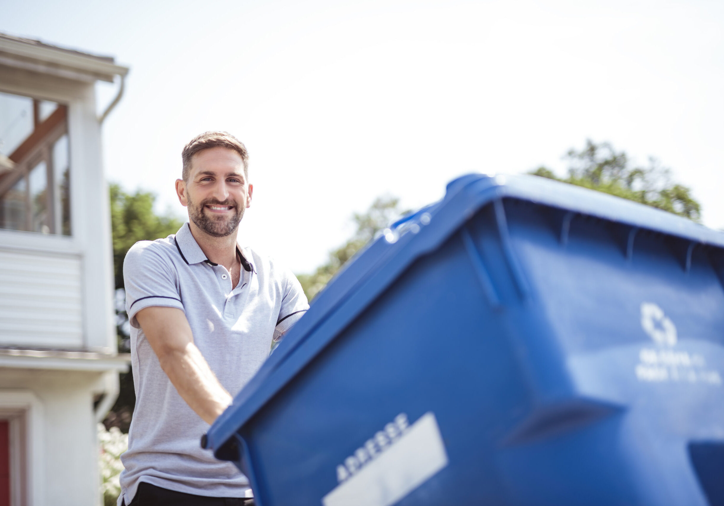 A Caucasian Man is Walking Outside His House in Order to Take Out recycling