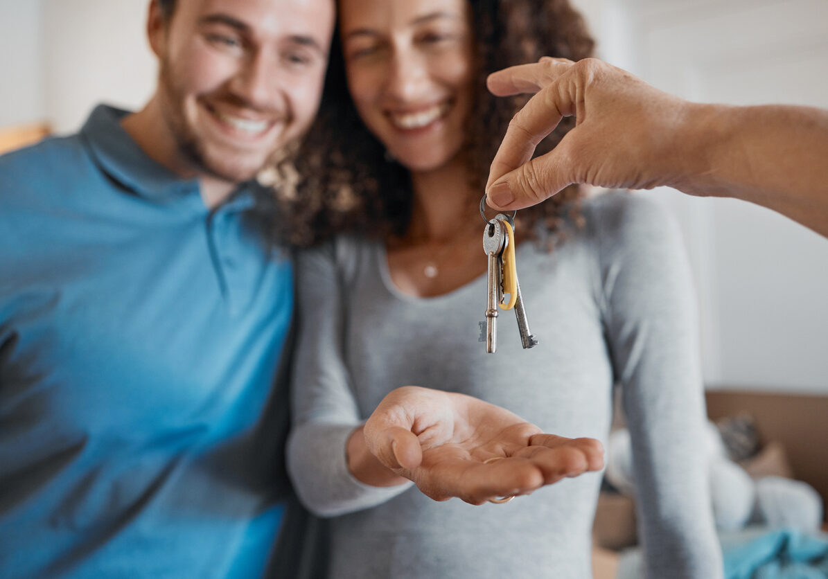 Hand, love or happy couple with house keys in real estate, property investment or buying apartment. New home blur, real estate agent giving or excited man with smile or woman to celebrate moving in together