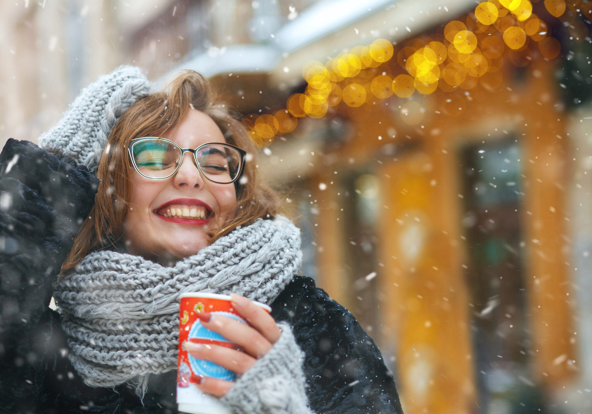 Excited lady with a cup of coffee walking in snowy weather