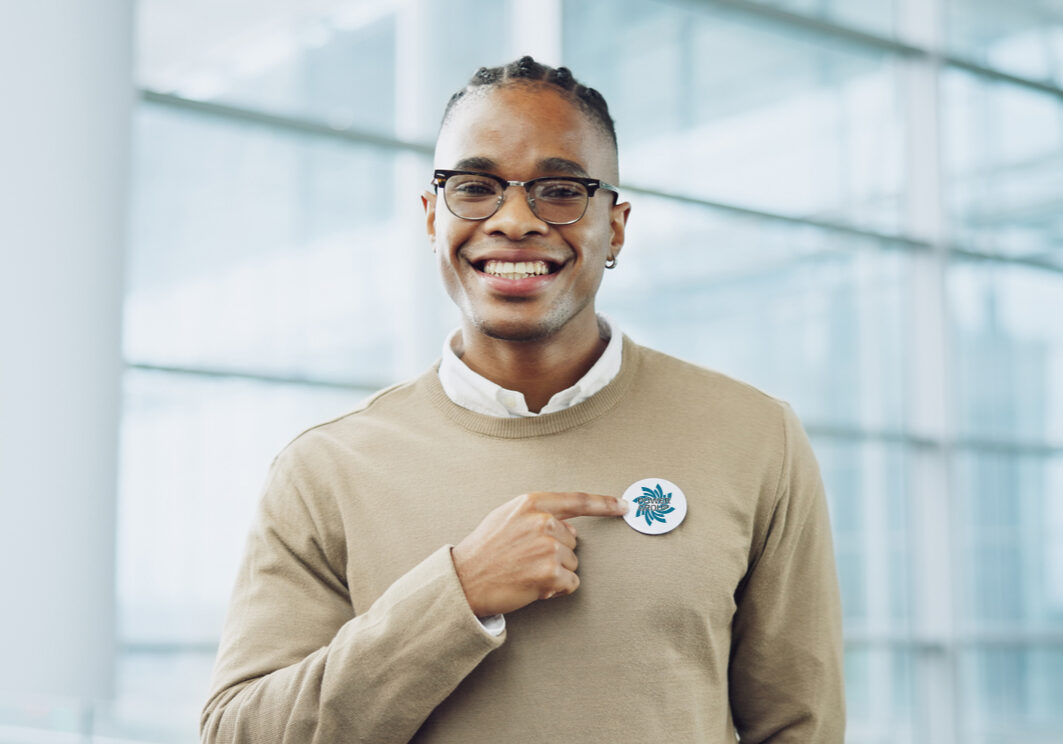 Man, portrait and badge for vote, smile and confidence or button, proud and choice in politics. Black person, happy and support for elections, democracy and party in registration for human rights