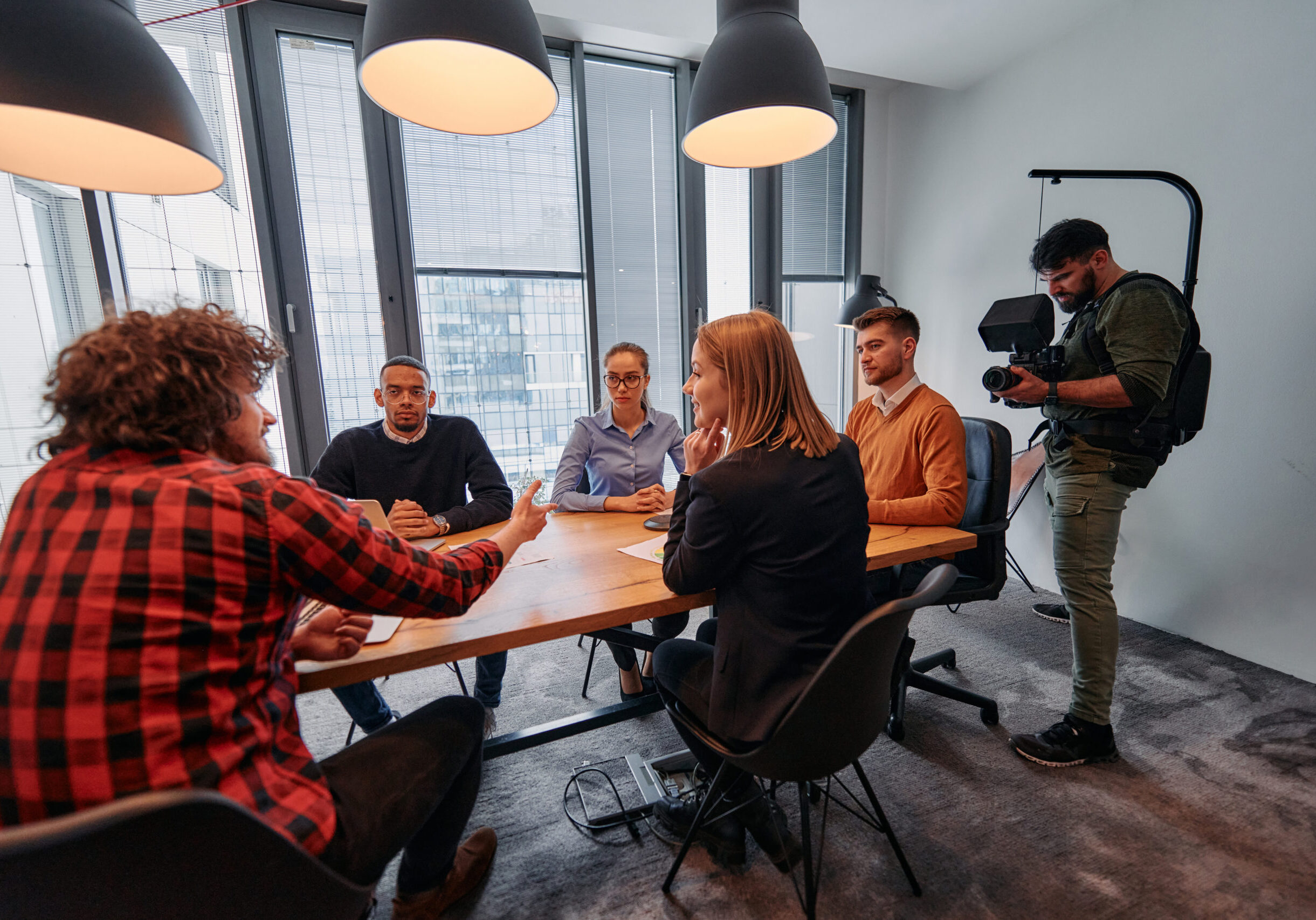 A videographer captures the essence of a business meeting in a modern office, skillfully documenting corporate dynamics and collaboration.