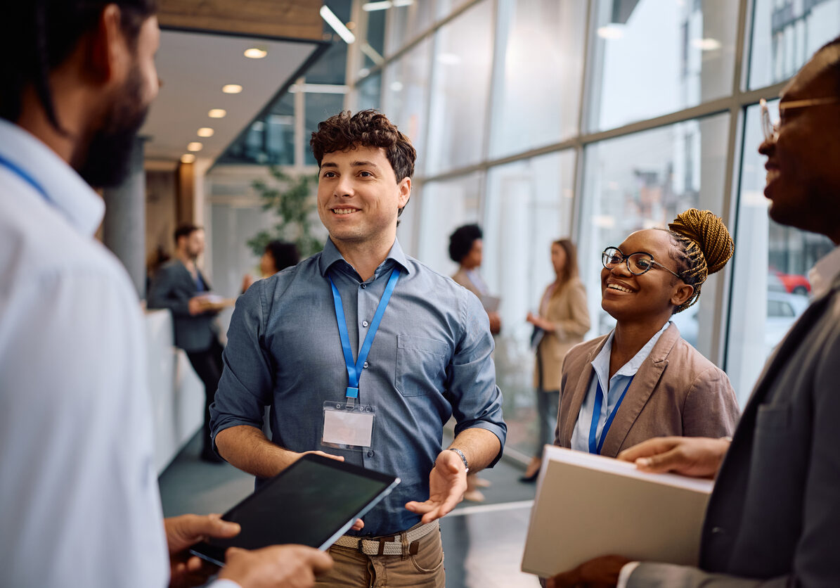 Multiracial group of happy business seminar attendees communicating in conference hall.