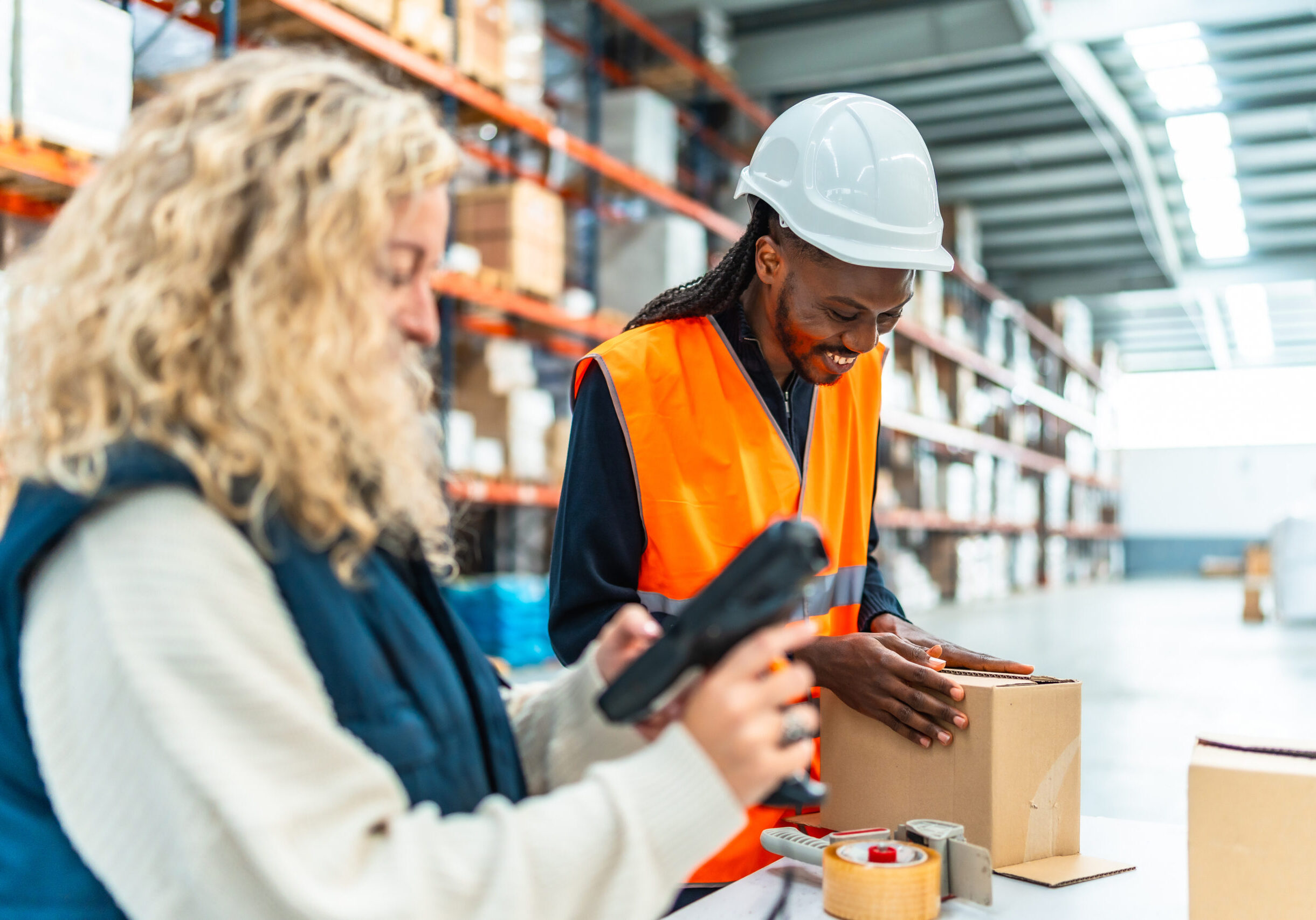 Multiracial female and male manual workers preparing boxes to deliver in a modern warehouse