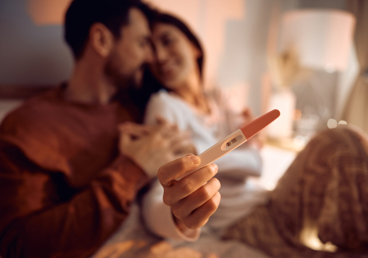 Close up of couple with positive pregnancy test.