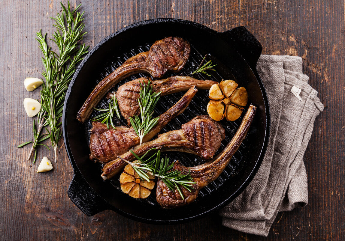 Roasted lamb ribs with rosemary and garlic on grill pan on dark wooden background