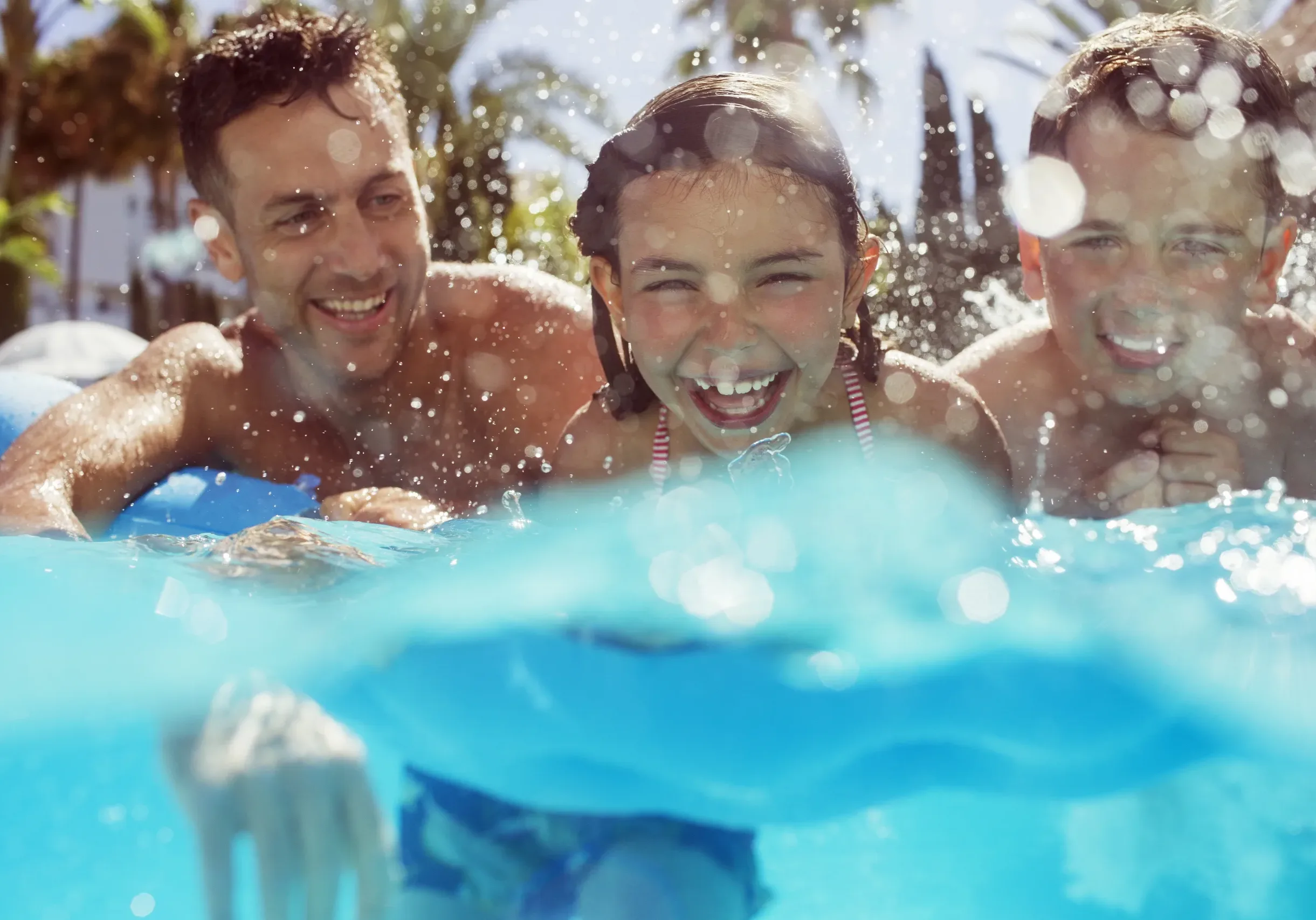 Father swimming with his two children in swimming pool