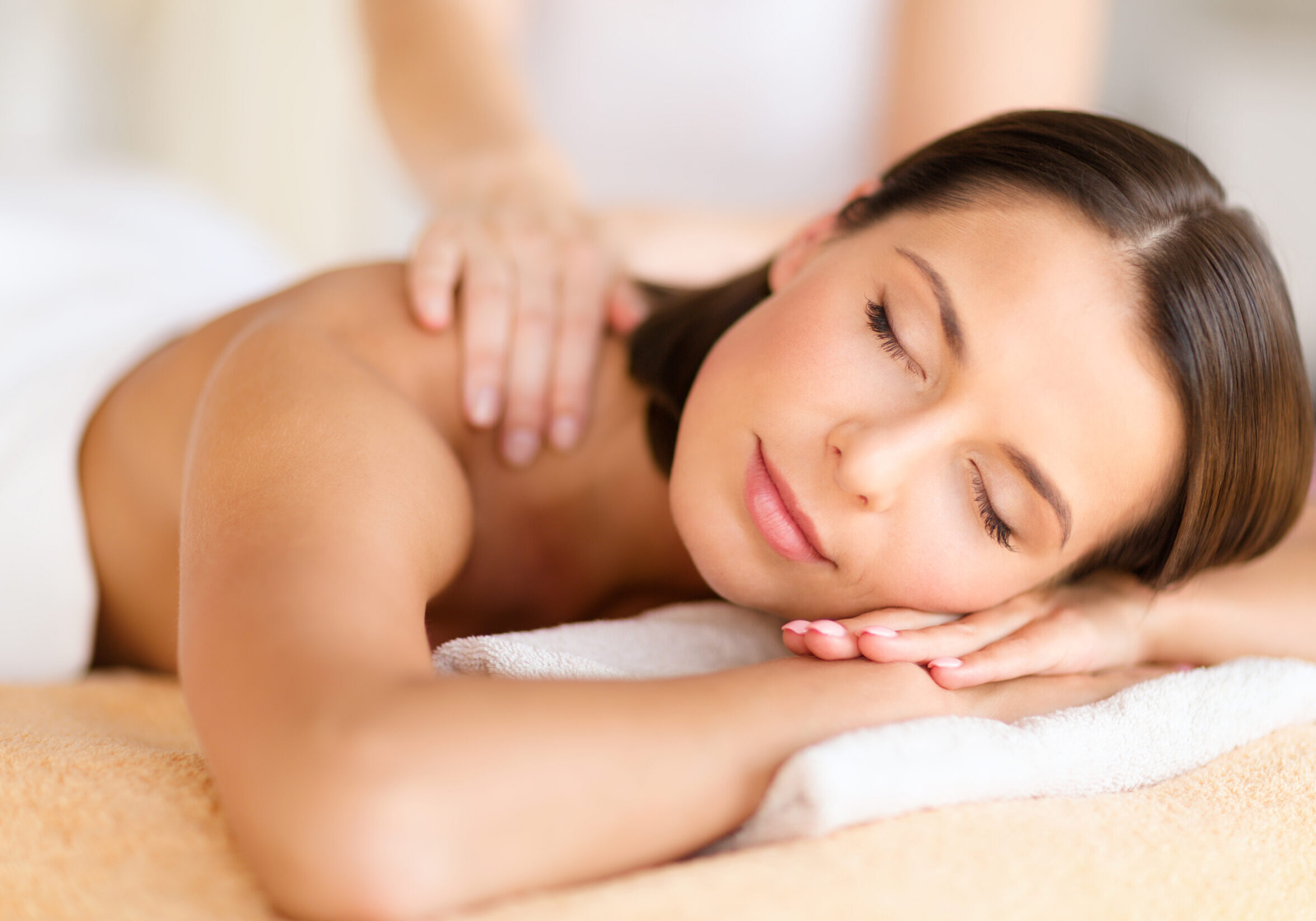 health, beauty, resort and relaxation concept - beautiful woman with closed eyes in spa salon getting massage