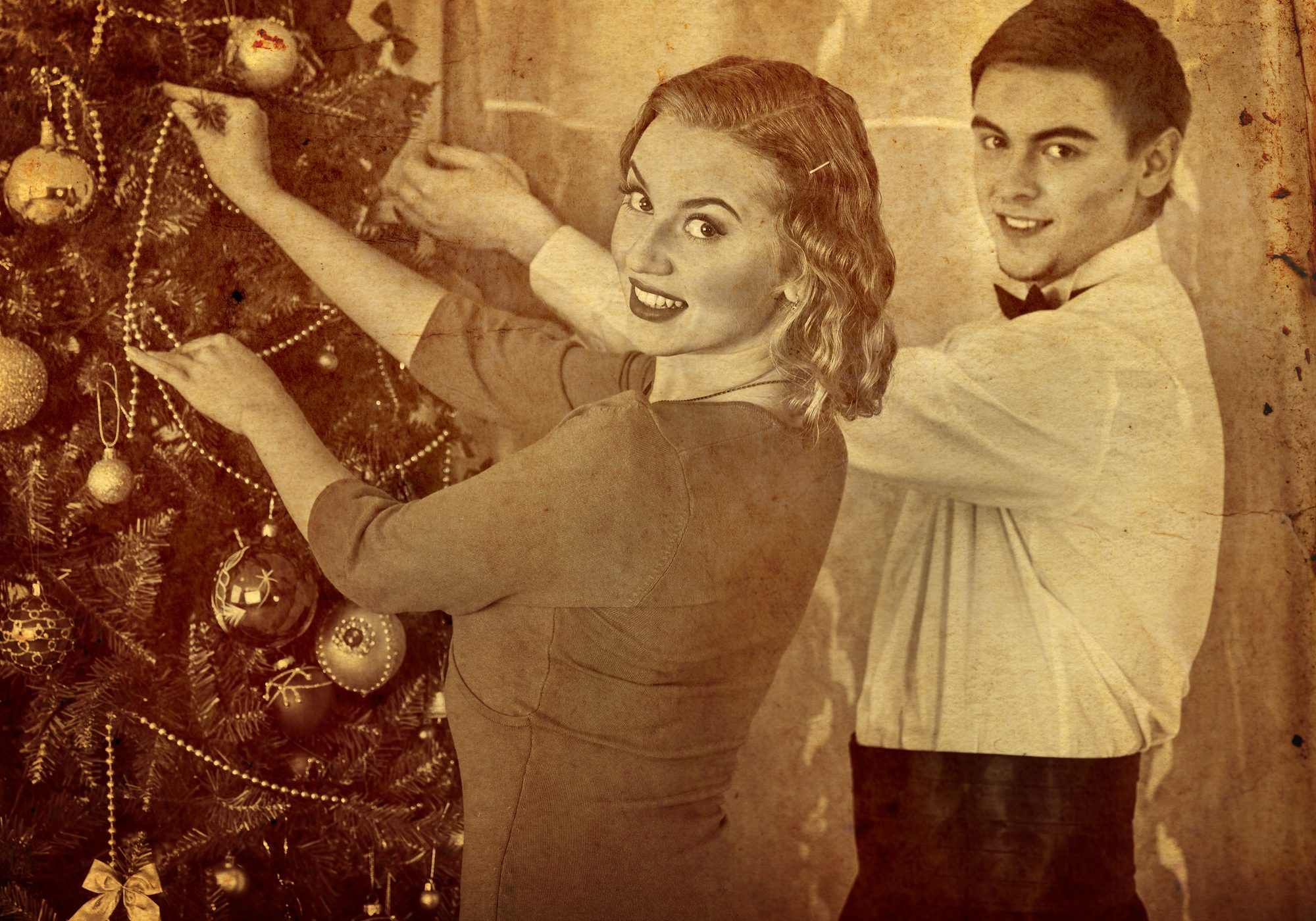 Old photo of loving couple preparing party near Christmas tree. Black and white retro picture.