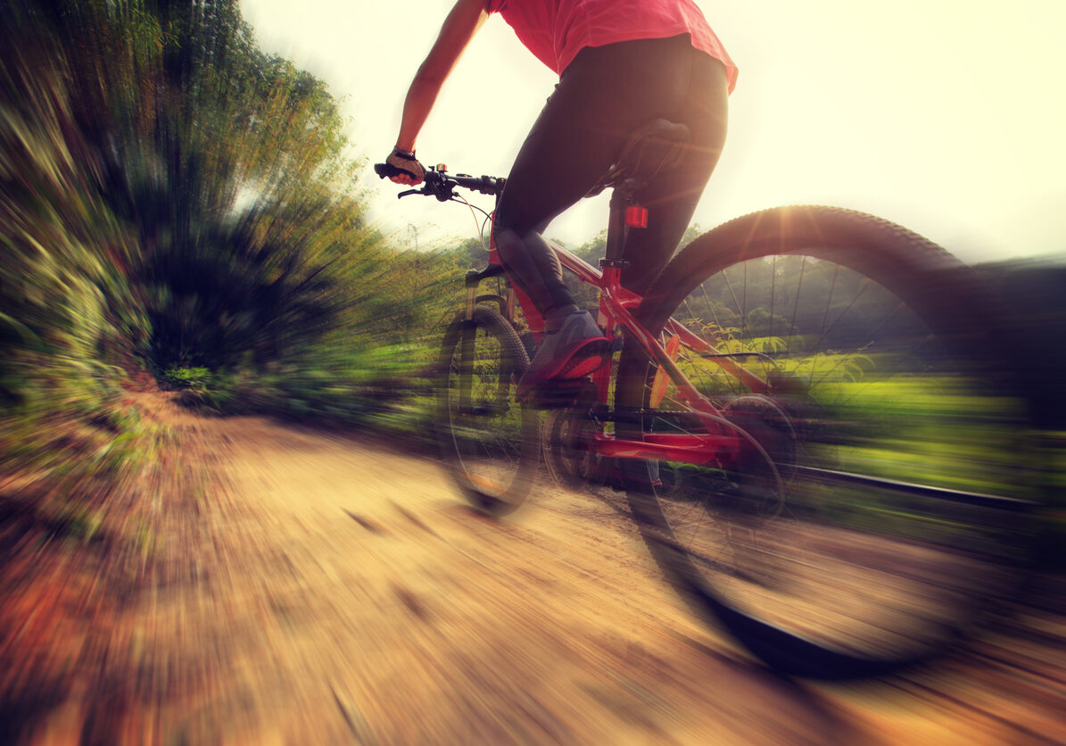 young woman riding mountain bike at sunrise forest trail