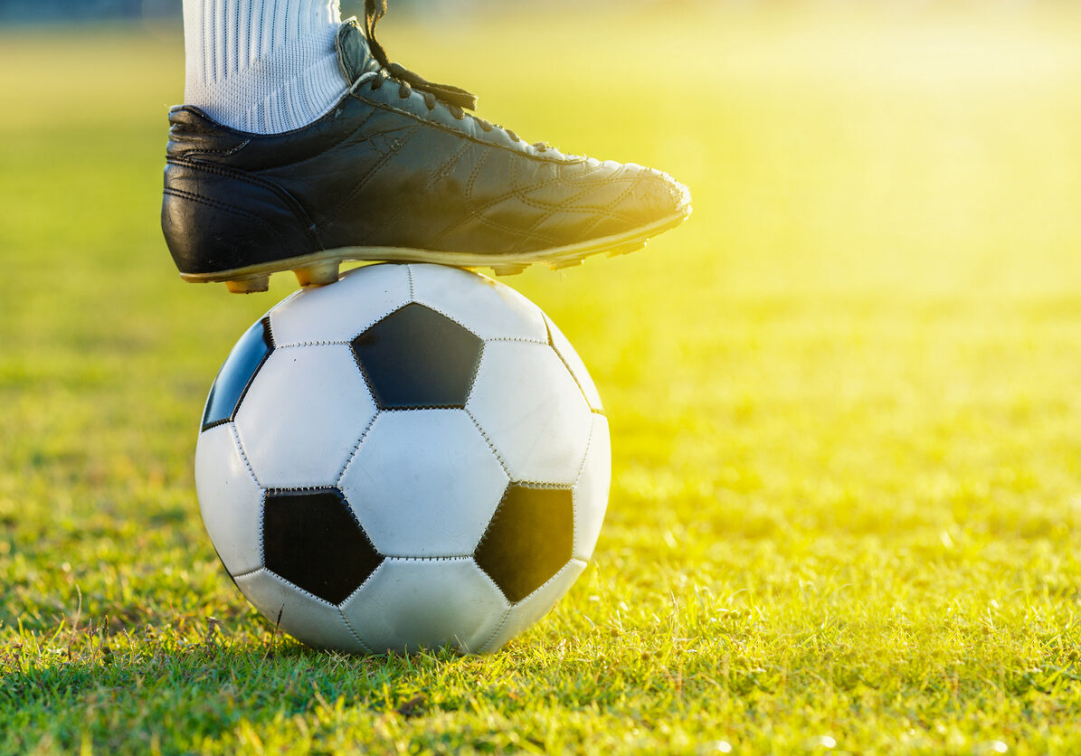 feet of soccer football player standing with the ball