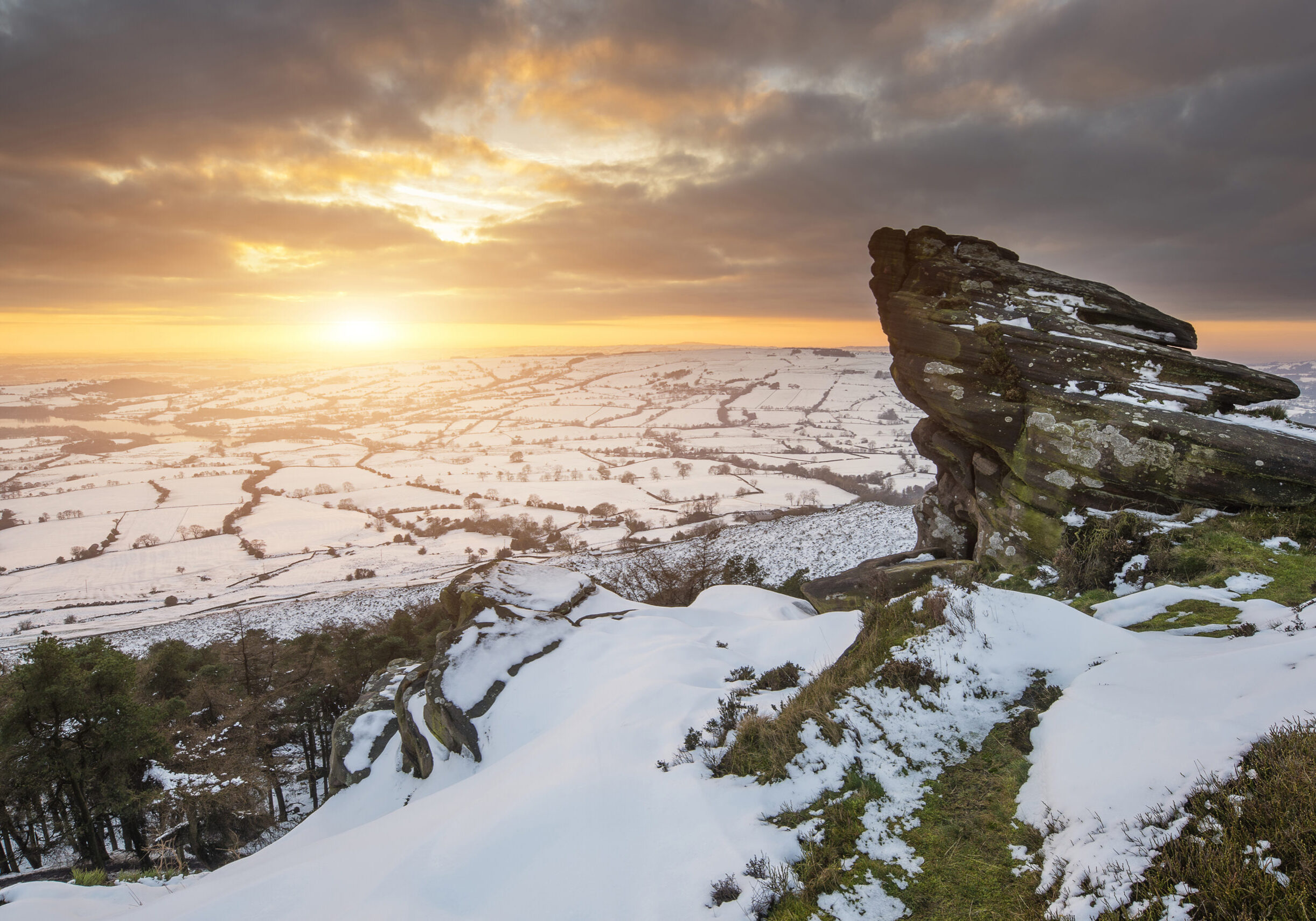 Winter sky over snow covered Winter landscape in Peak District at sunset