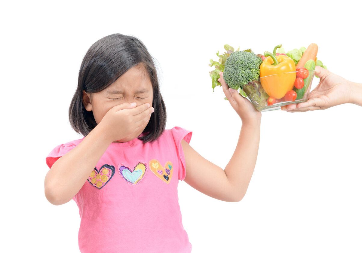 girl with expression of disgust against vegetables